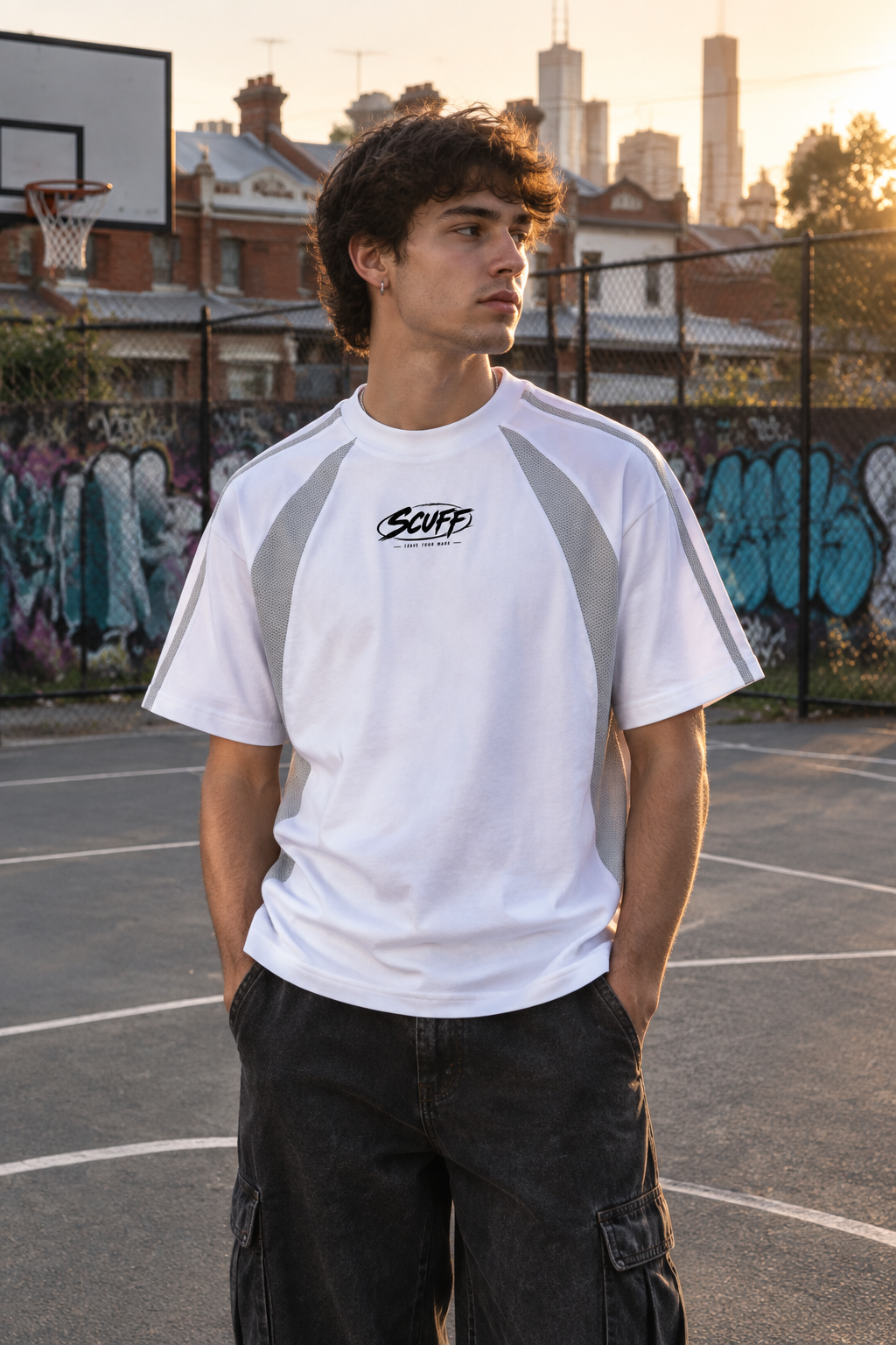 Man wearing the white and grey SCUFF Stick Rider Raglan Color T-Shirt on an outdoor basketball court in inner city Melbourne